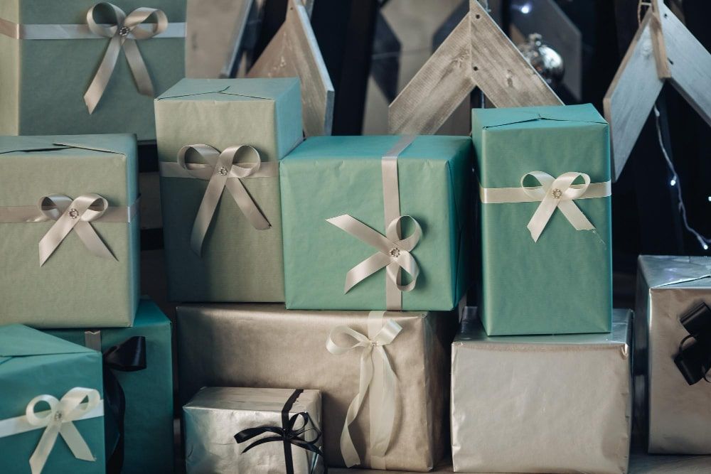 A close-up view of numerous gift-wrapped wedding client gifts adorned with bows neatly stacked on the floor