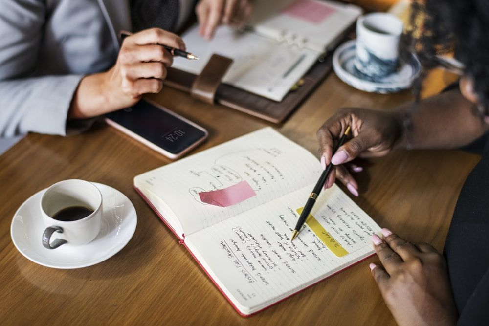 Business partners strategizing over a cafe meeting, coupled with closing sales strategies, capturing collaborative planning for successful business outcomes and figuring out what event gifts to give out