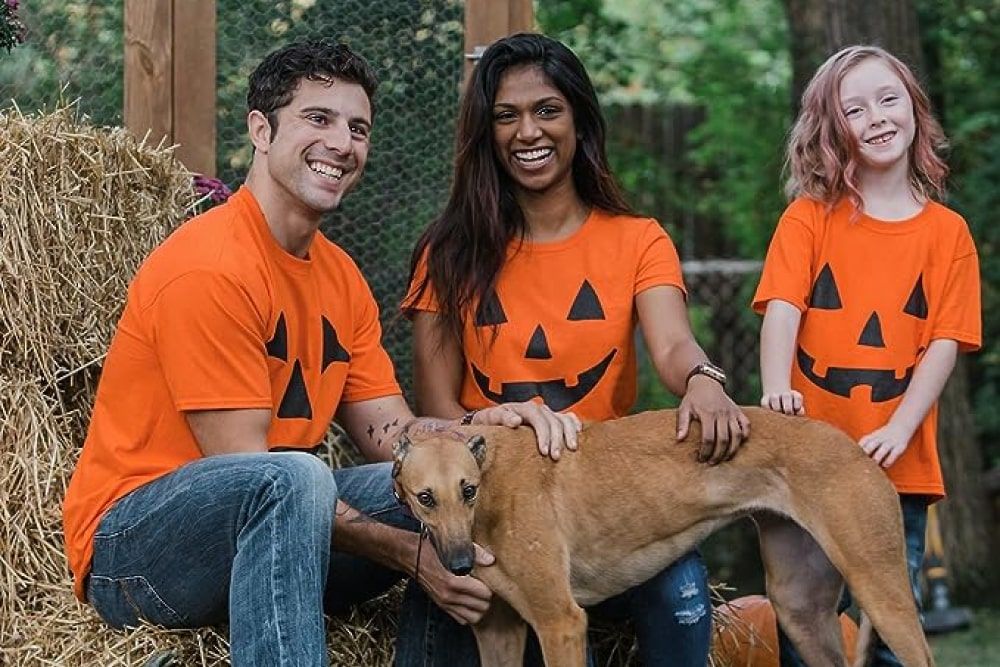 Family wearing cute pumpkin shirts with their dog