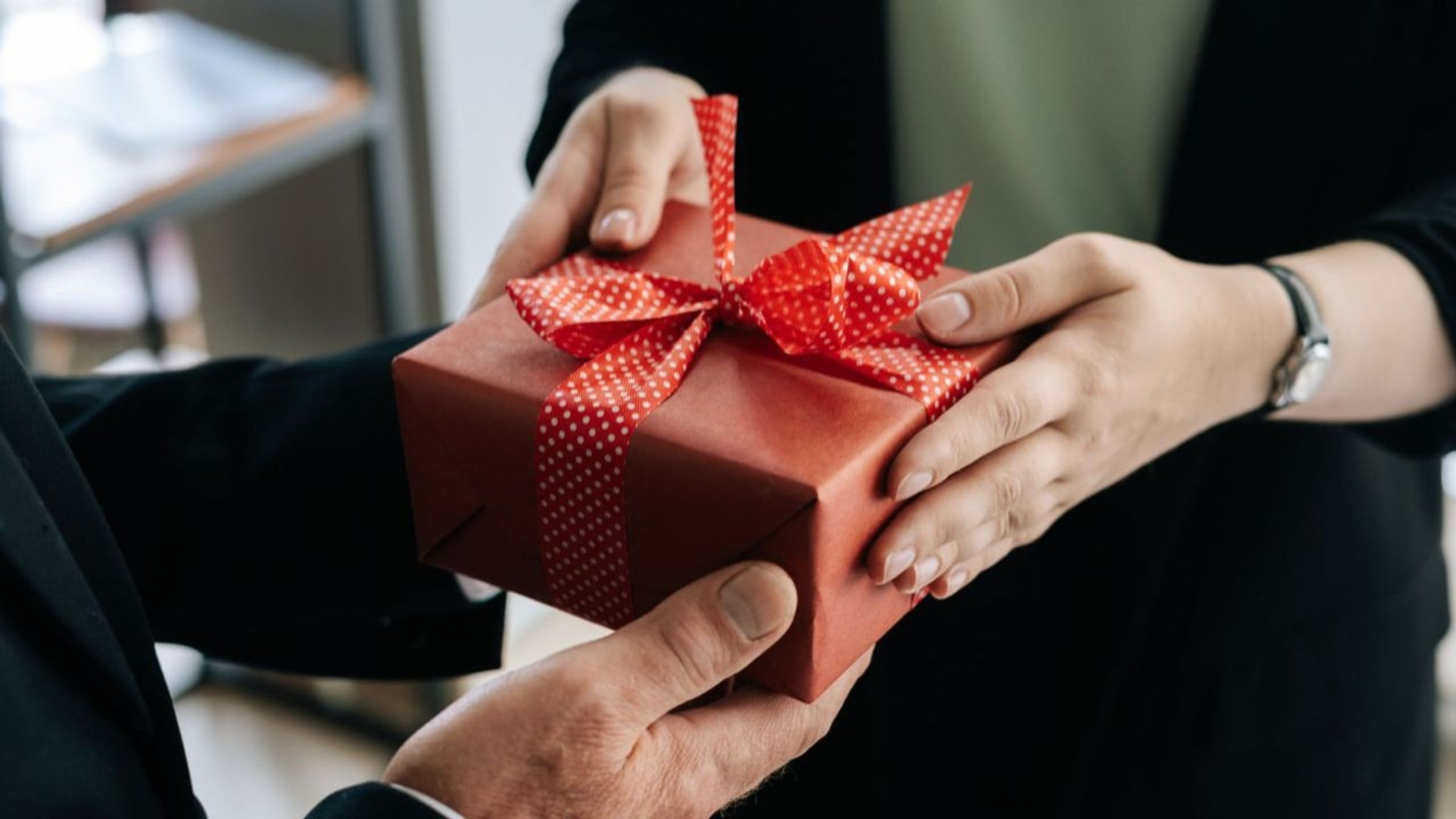 coworker handing coworker appreciation gifts to their friend at work