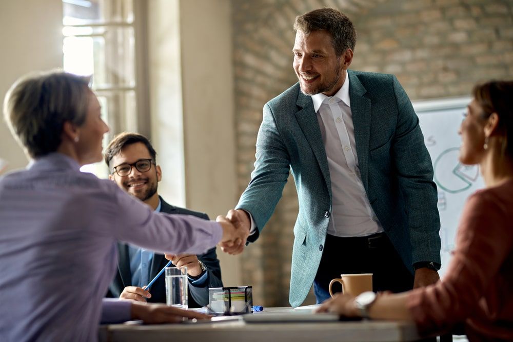 Office handshake among colleagues meets successful sales closure, epitomizing triumphant business interactions after sharing gifts for business partners