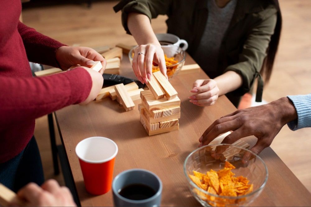 Photo of friends having fun, playing traditional games like Jenga, and enjoying snacks together