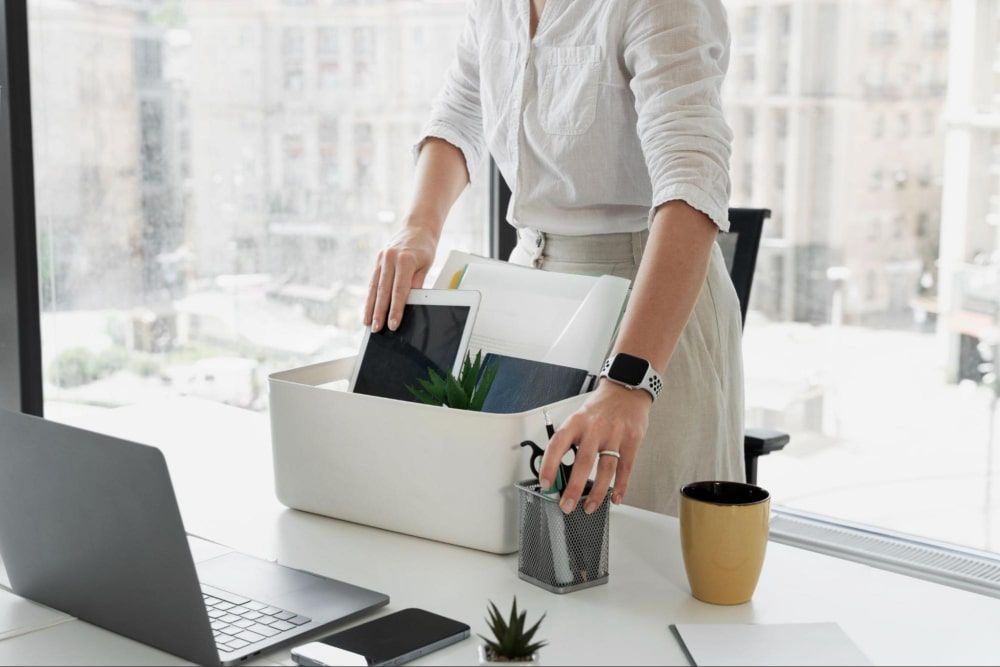 Side view of a woman packing her desk items in a box, ready to leave the company