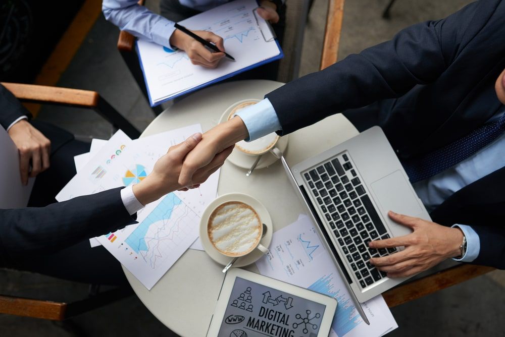 Symbolic handshake image merged with the concept of closing deals and making sales, epitomizing successful business negotiations and planning to share client appreciation gifts