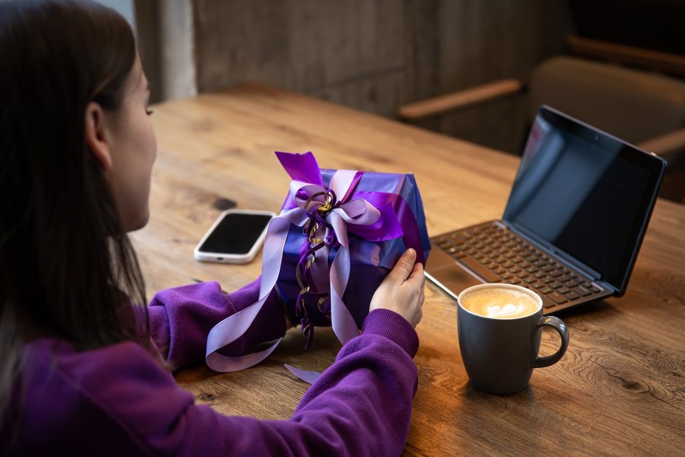 Woman holding purple gift box, paired with closing sales gifting, embodies strategic success