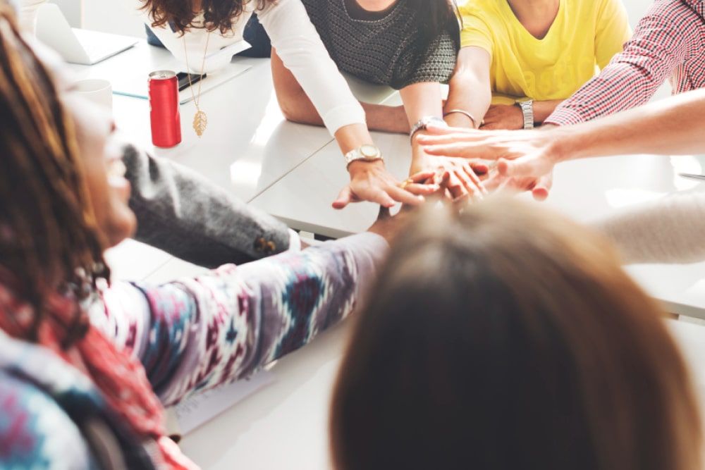 a group of individuals uniting hands as a cohesive team for how to improve employee morale