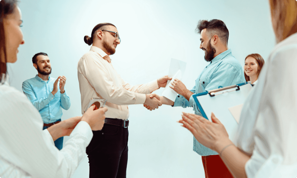 boss congratulating young successful employee after knowing how to improve employee morale