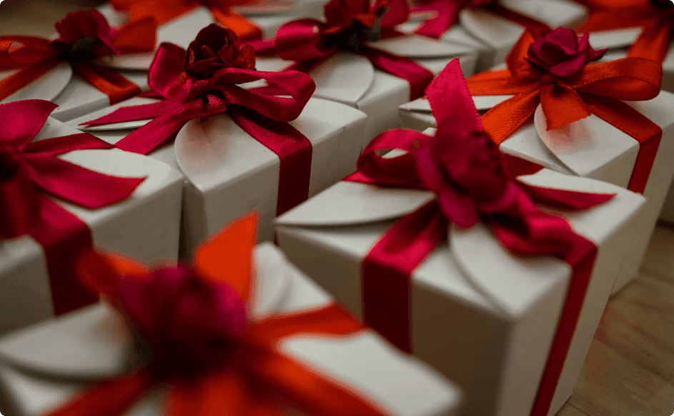 Many bulk client gifts wrapped in golden wrapping paper with red ribbon