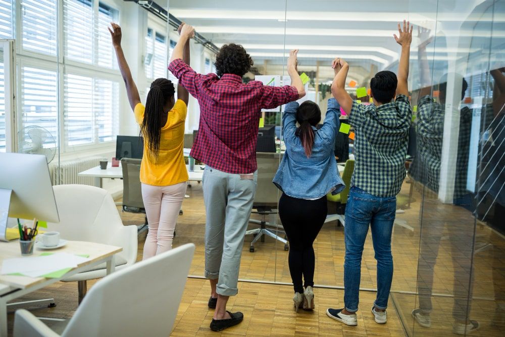 business professionals triumphantly lifting their arms in an office