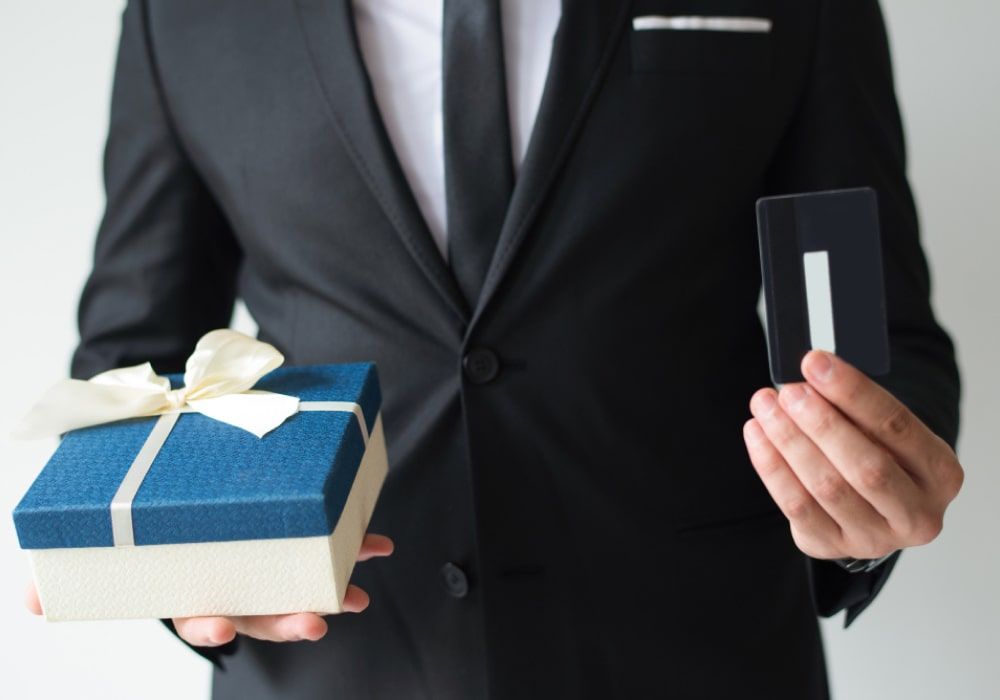 businessman holding gift and credit card as he plans on buying ceo gifts for his ceo