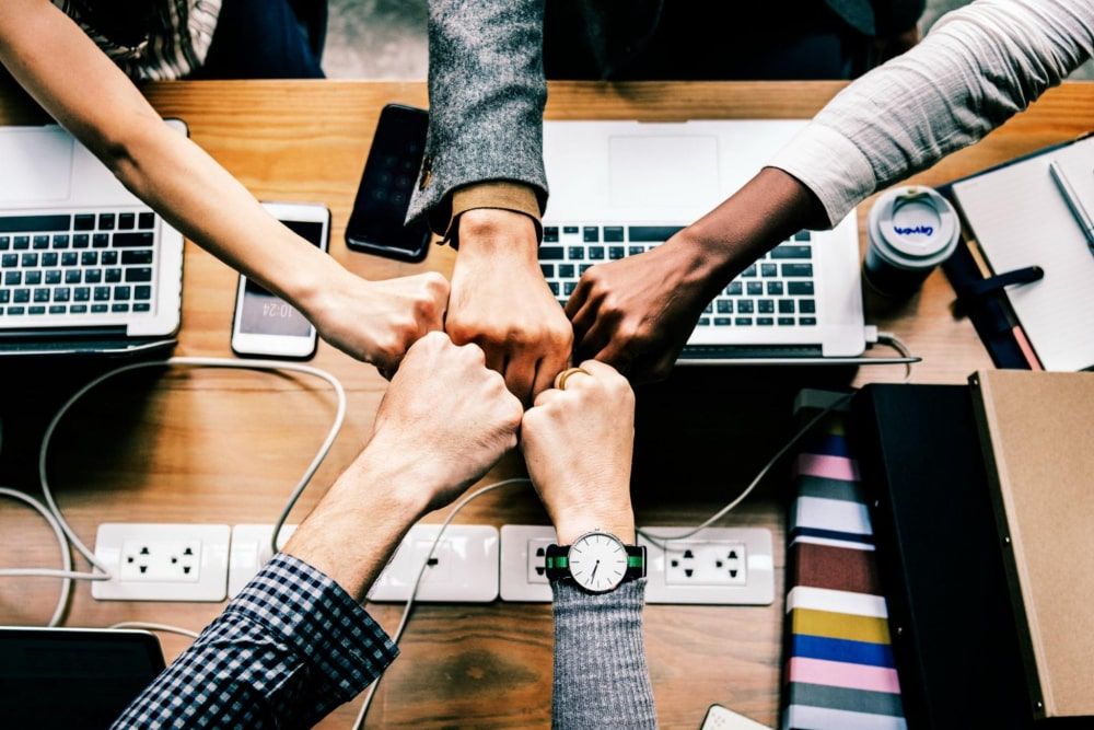 colleagues giving a friendly fist bump in the office after receiving office gifts for employees