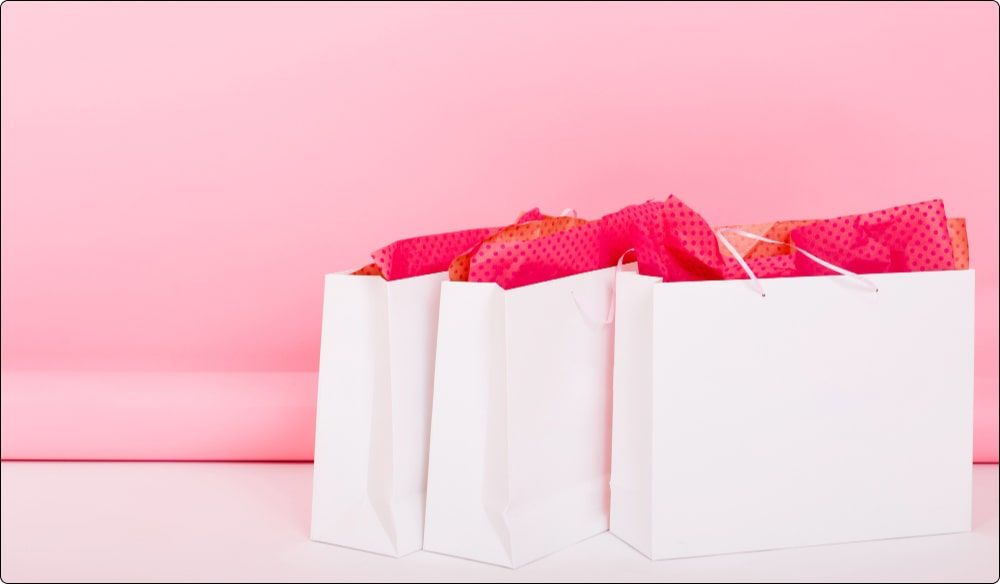 cute swag bags with wrapping paper lying on the floor on pink background