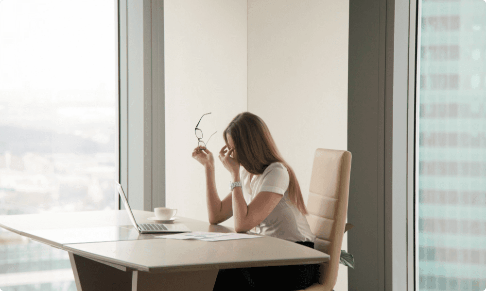 exhausted businesswoman sitting at office thinking about employee rewards and recognition program examples