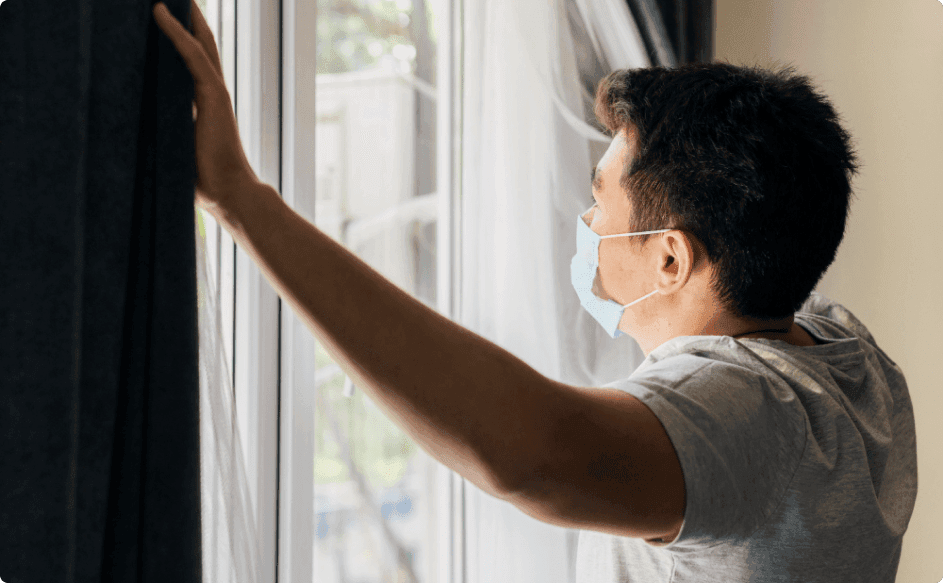 man looking out of window craving human interaction