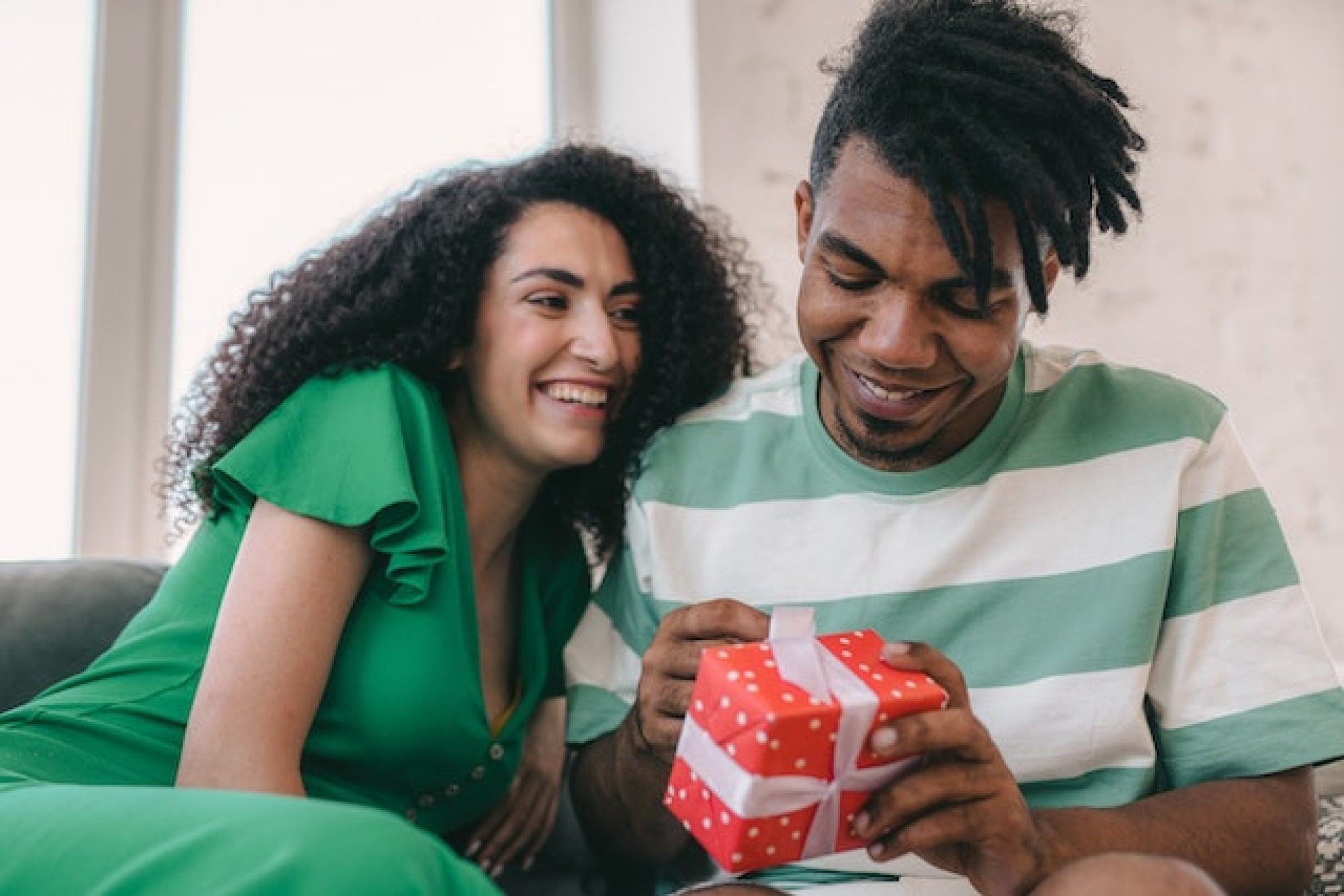 man opening his valentines day gift with woman leaning against his shoulder
