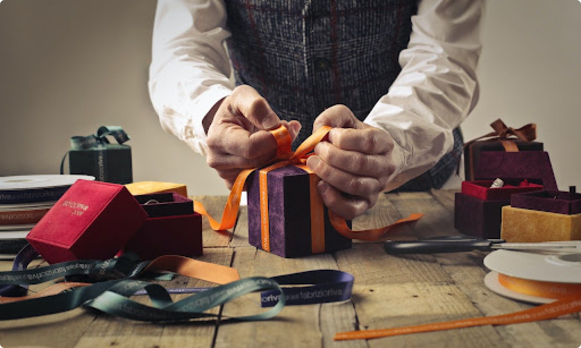 man packing gifts with beautiful ribbons and gift boxes as one of the many gift ideas for staff