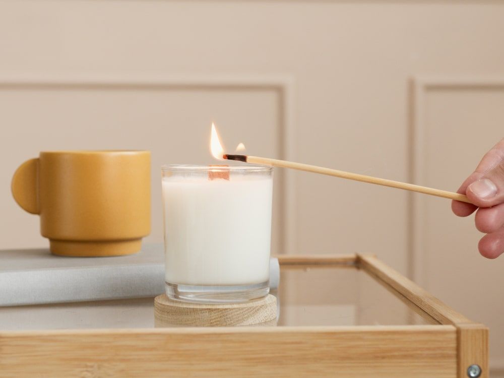 person lighting up a scented candle with a match