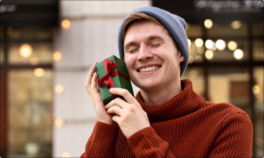 smiling man loving the christmas gifts - christmas gifts for employees