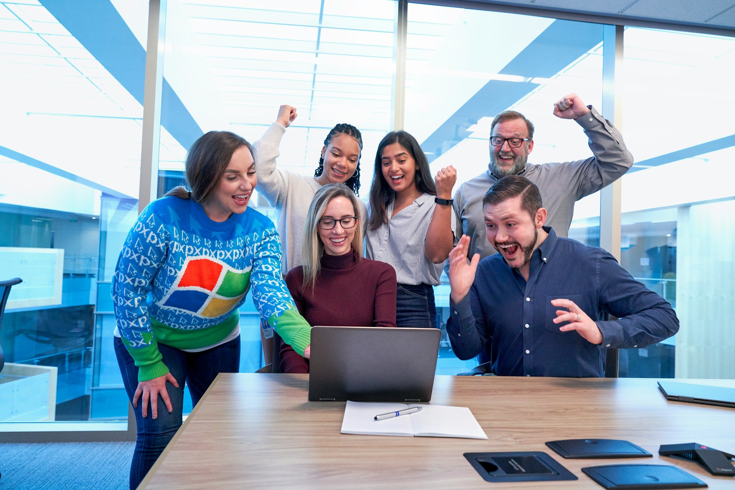 team looking at laptop and looking happy - Holiday Team Building Activities