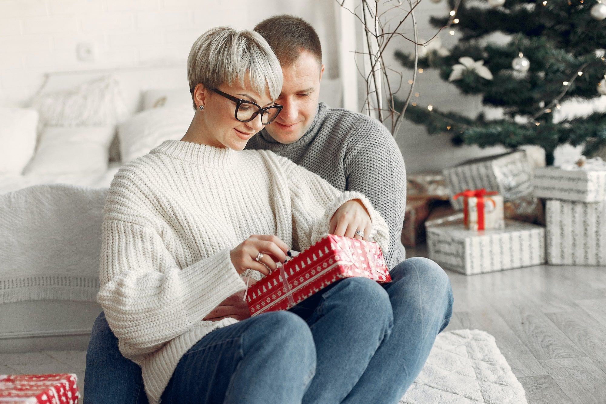 woman opening her valentines day gift with man watching