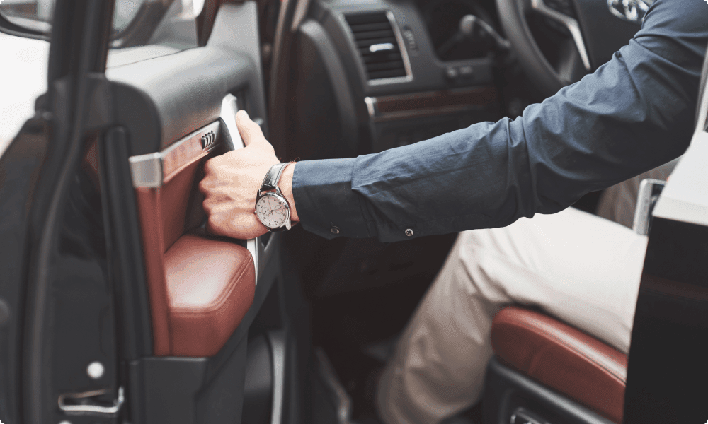 young man in full suit while driving a luxury car