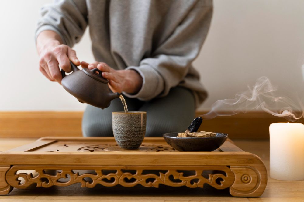 young woman relaxing at home with tea and burning sage